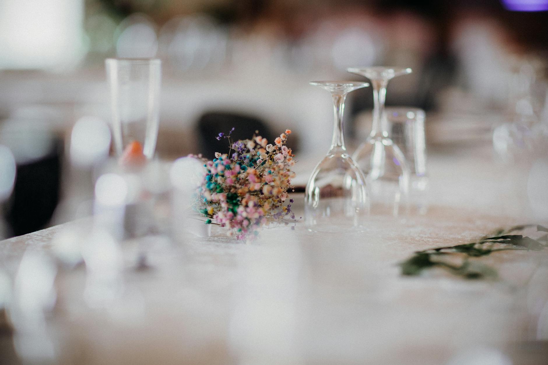 Rustic table setting with delicate floral centerpiece and upside-down wine glasses.