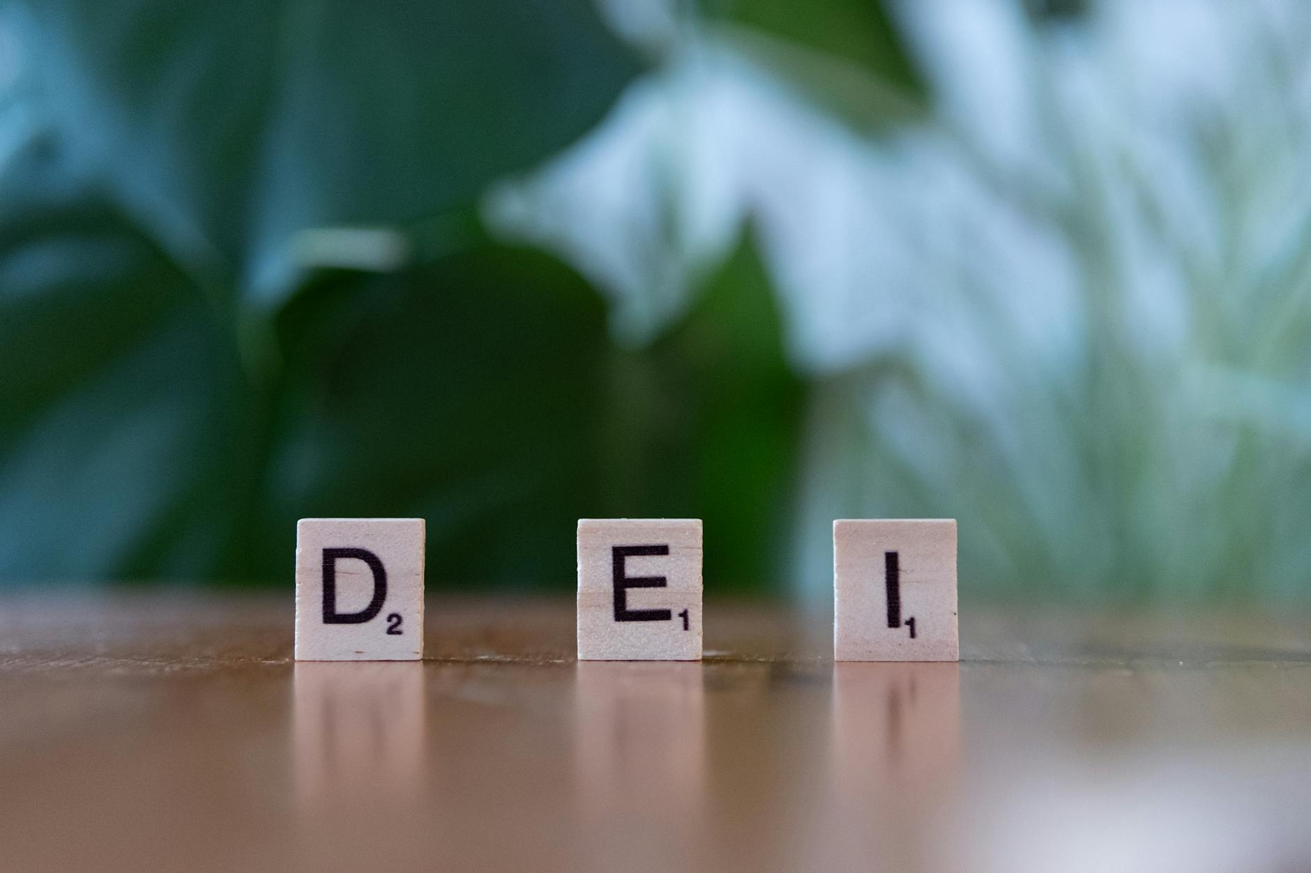 Wooden letter tiles spelling 'DEI' on a table symbolizing diversity, equity, and inclusion.