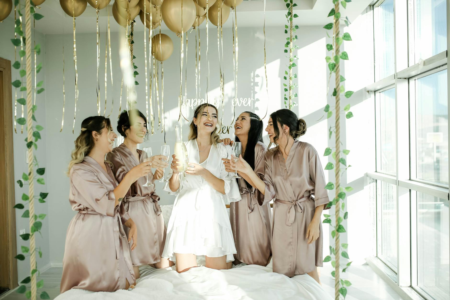 A radiant bride celebrates with bridesmaids in a joyful pre-wedding gathering indoors.