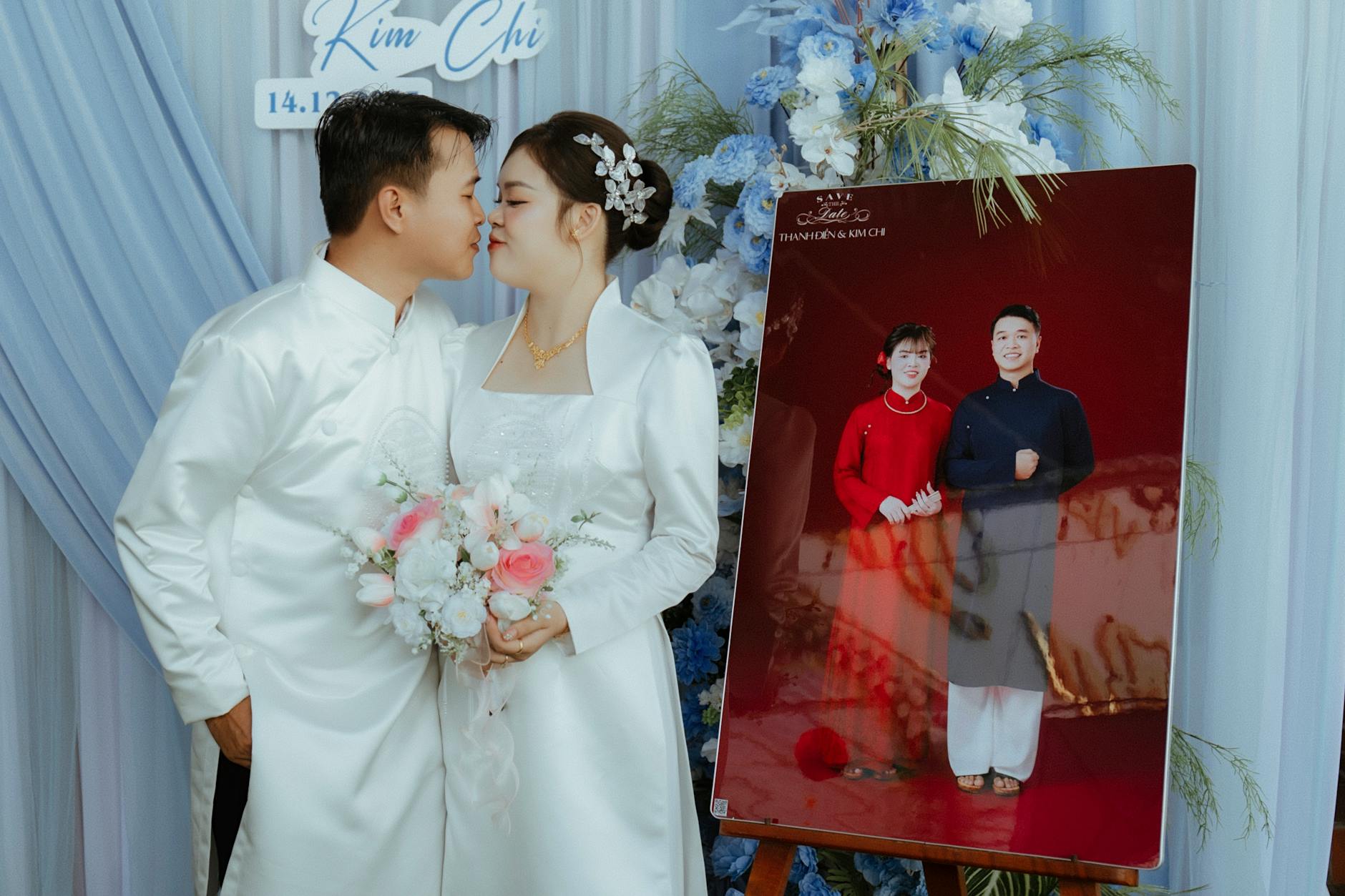 Bride and groom share a kiss during their wedding in elegant attire with floral decoration.