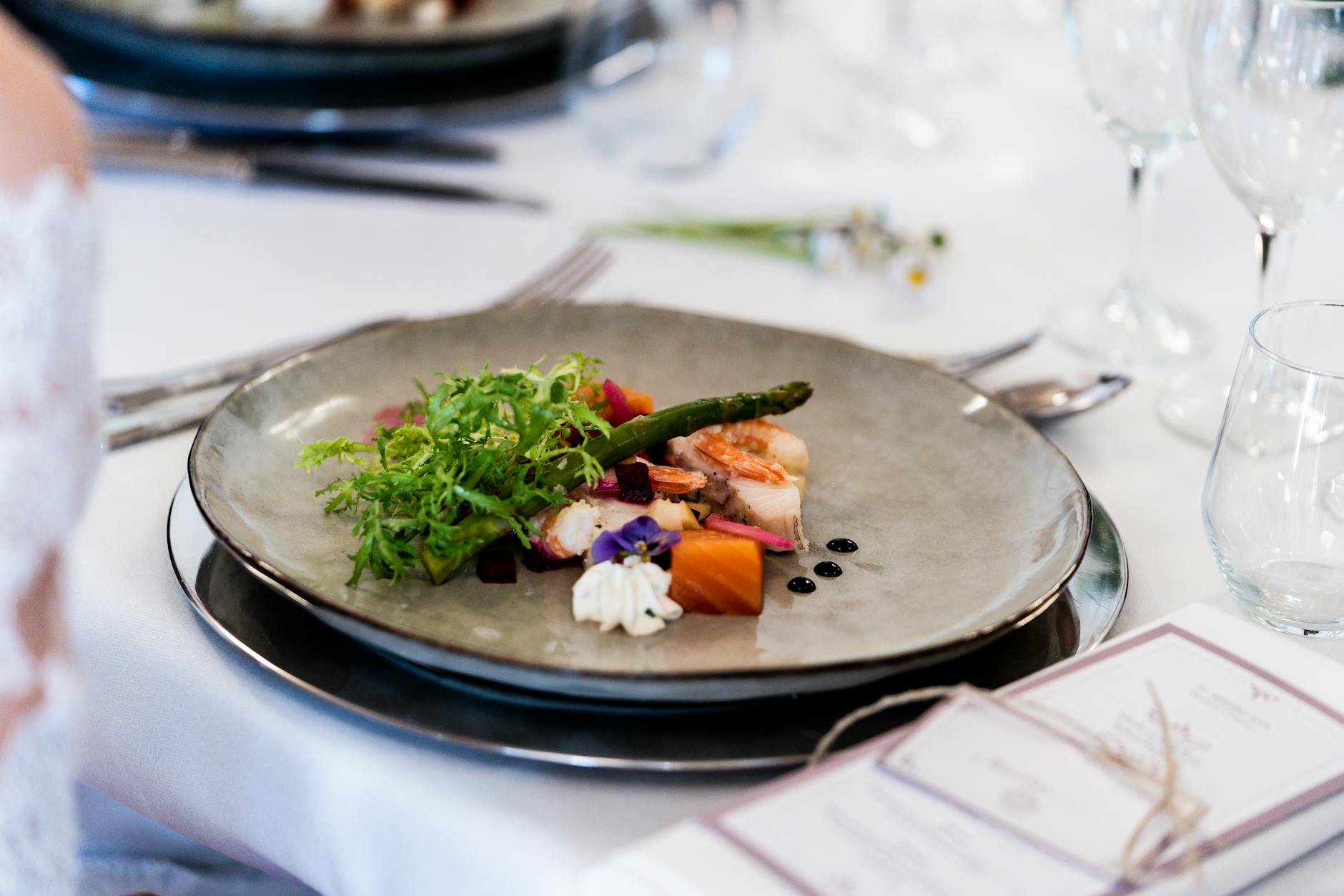 A gourmet dish with vegetables and sauce elegantly presented at a sophisticated table setting.