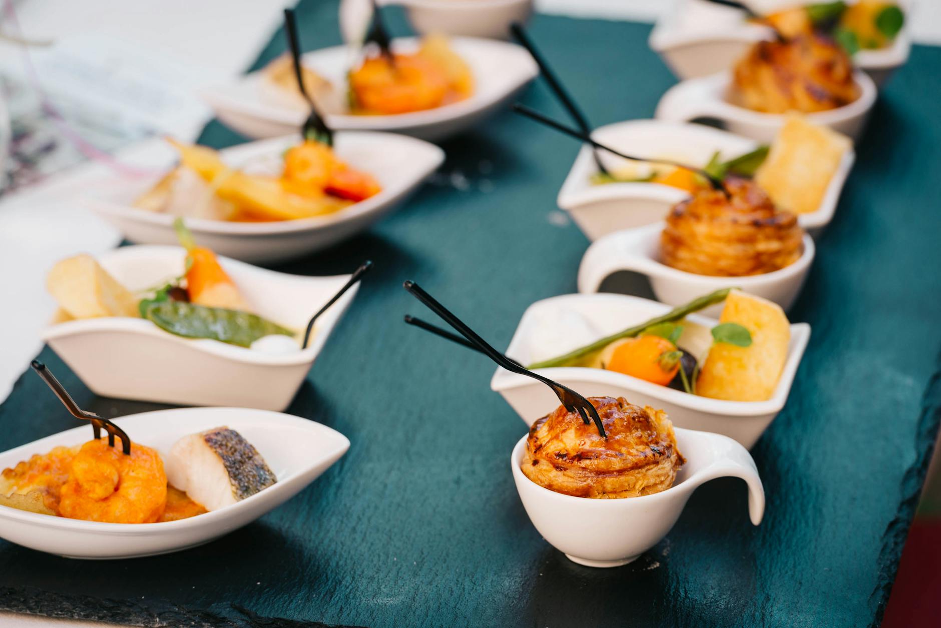 A selection of gourmet canapés beautifully arranged on a black slate tray for a sophisticated presentation.