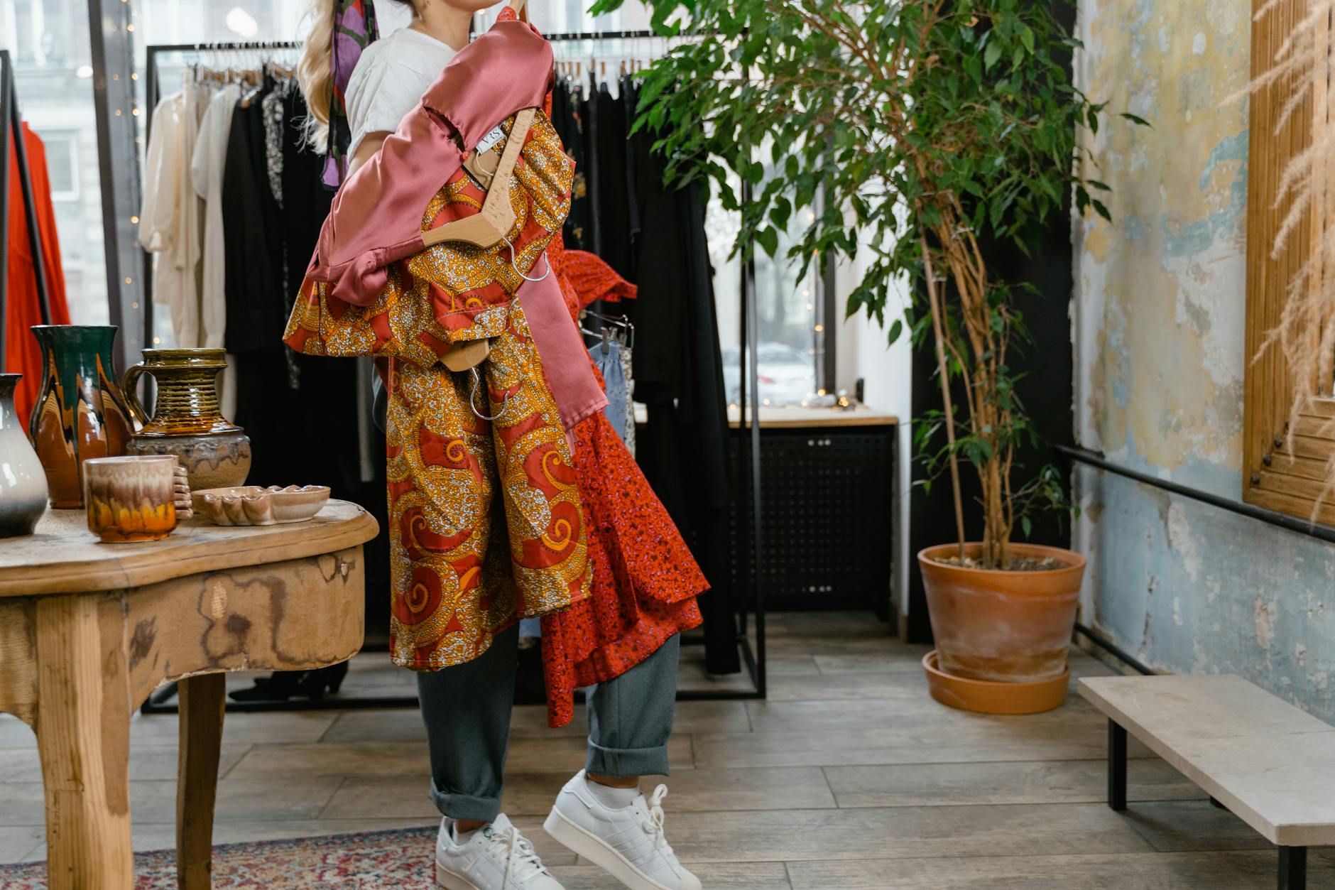 A woman holding colorful garments in a chic fashion store with elegant decor.